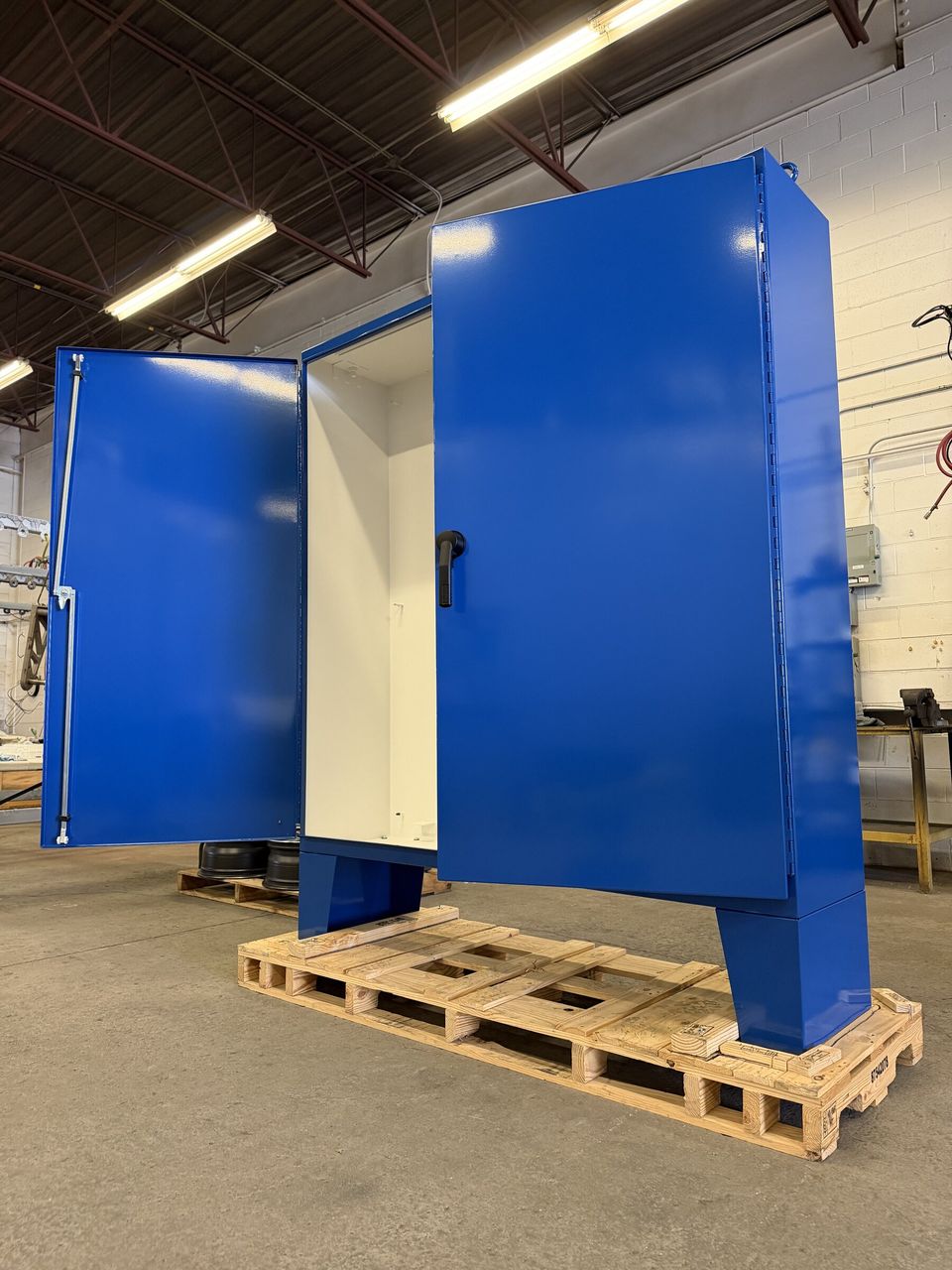 Blue powder-coated electrical cabinet with open doors in the MMC shop