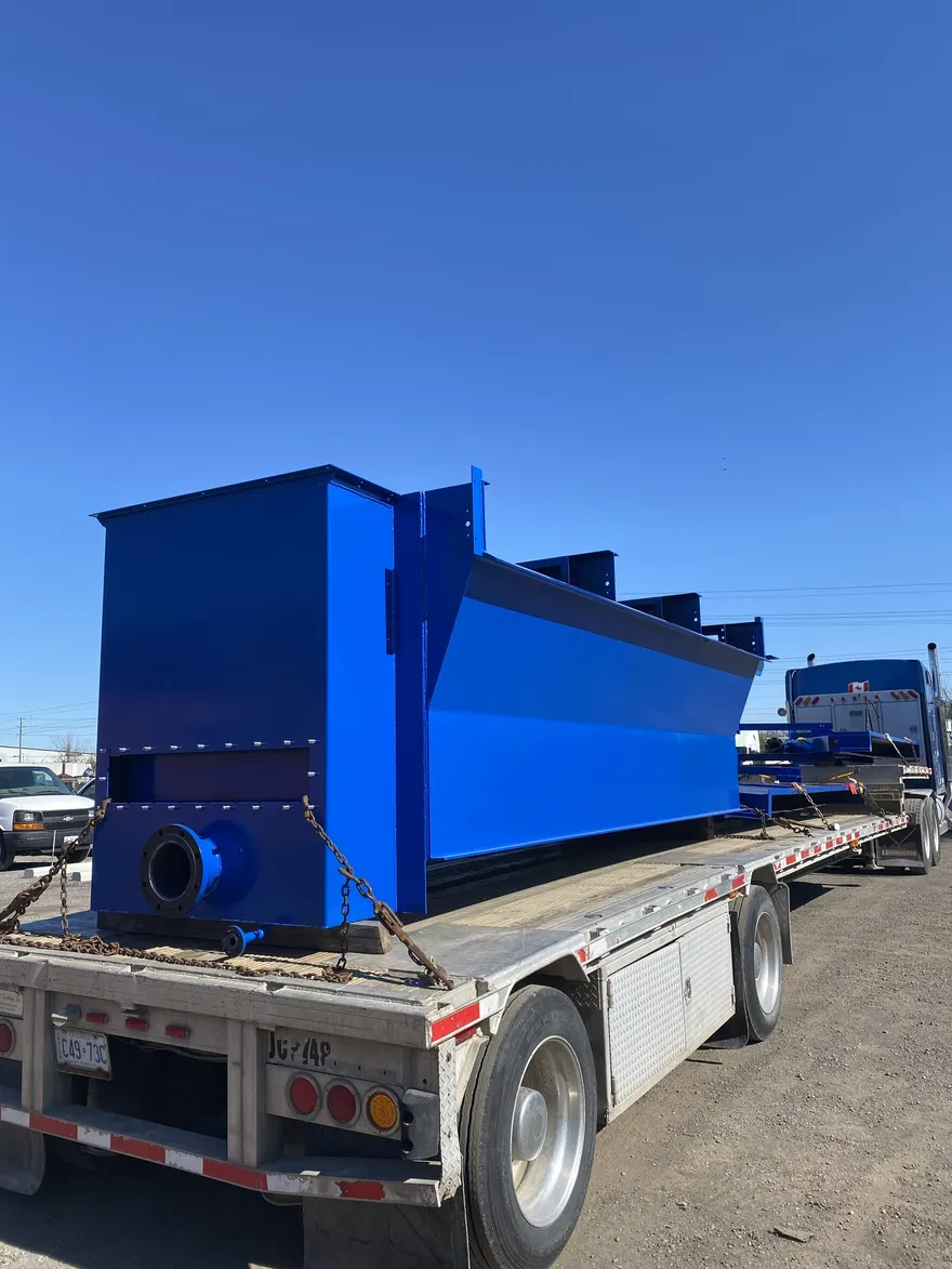 Large blue powder-coated hopper strapped to a flatbed trailer
