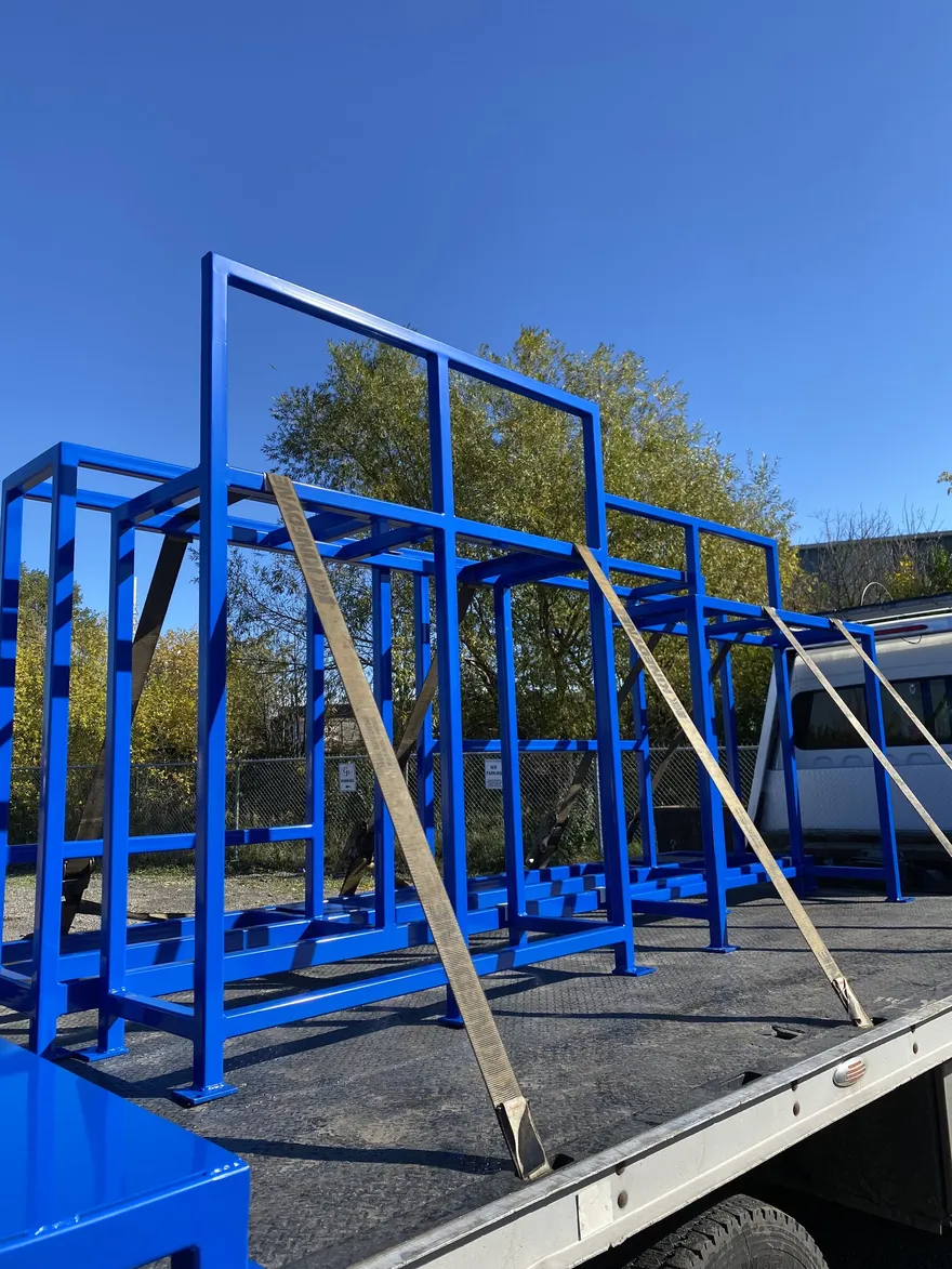 Blue powder-coated steel racks loaded on a flatbed