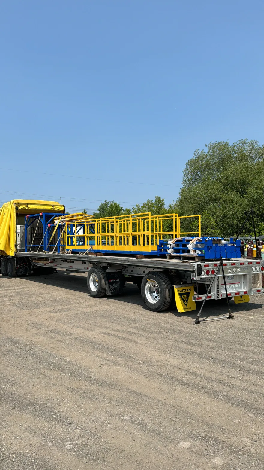Flatbed trailer loaded with yellow and blue powder-coated racks